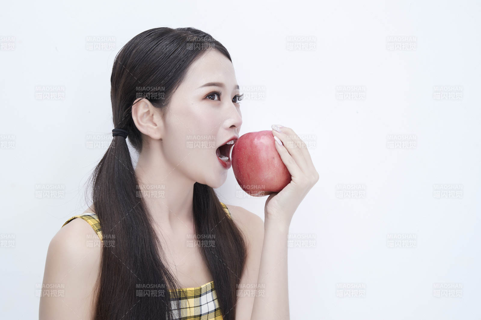 手拿苹果身穿格子吊带裙的亚洲可爱少女人像图片