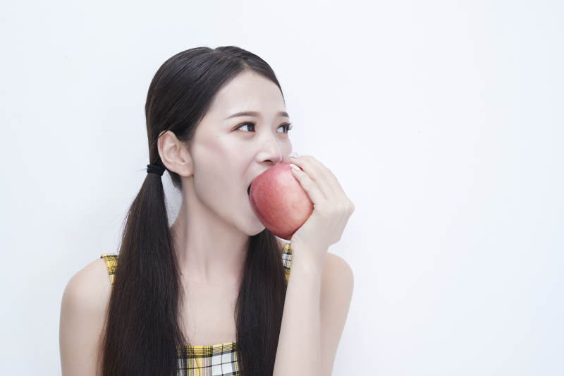 手拿苹果身穿格子吊带裙的亚洲可爱少女人像图片