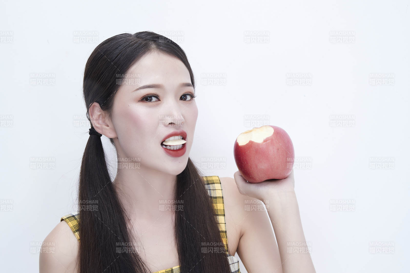 手拿苹果身穿格子吊带裙的亚洲可爱少女人像图片