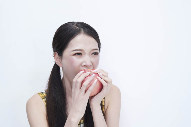 手拿苹果身穿格子吊带裙的亚洲可爱少女人像图片