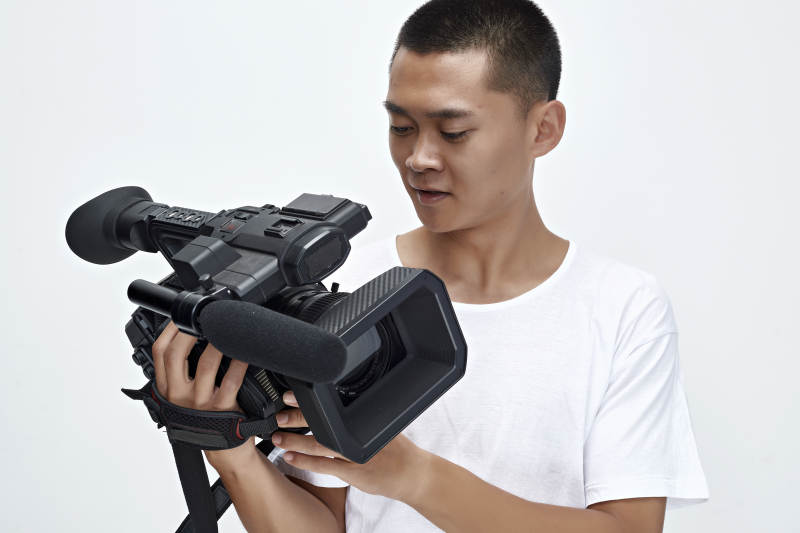 白色背景下手持摄像机进行录制拍摄的摄像师图片