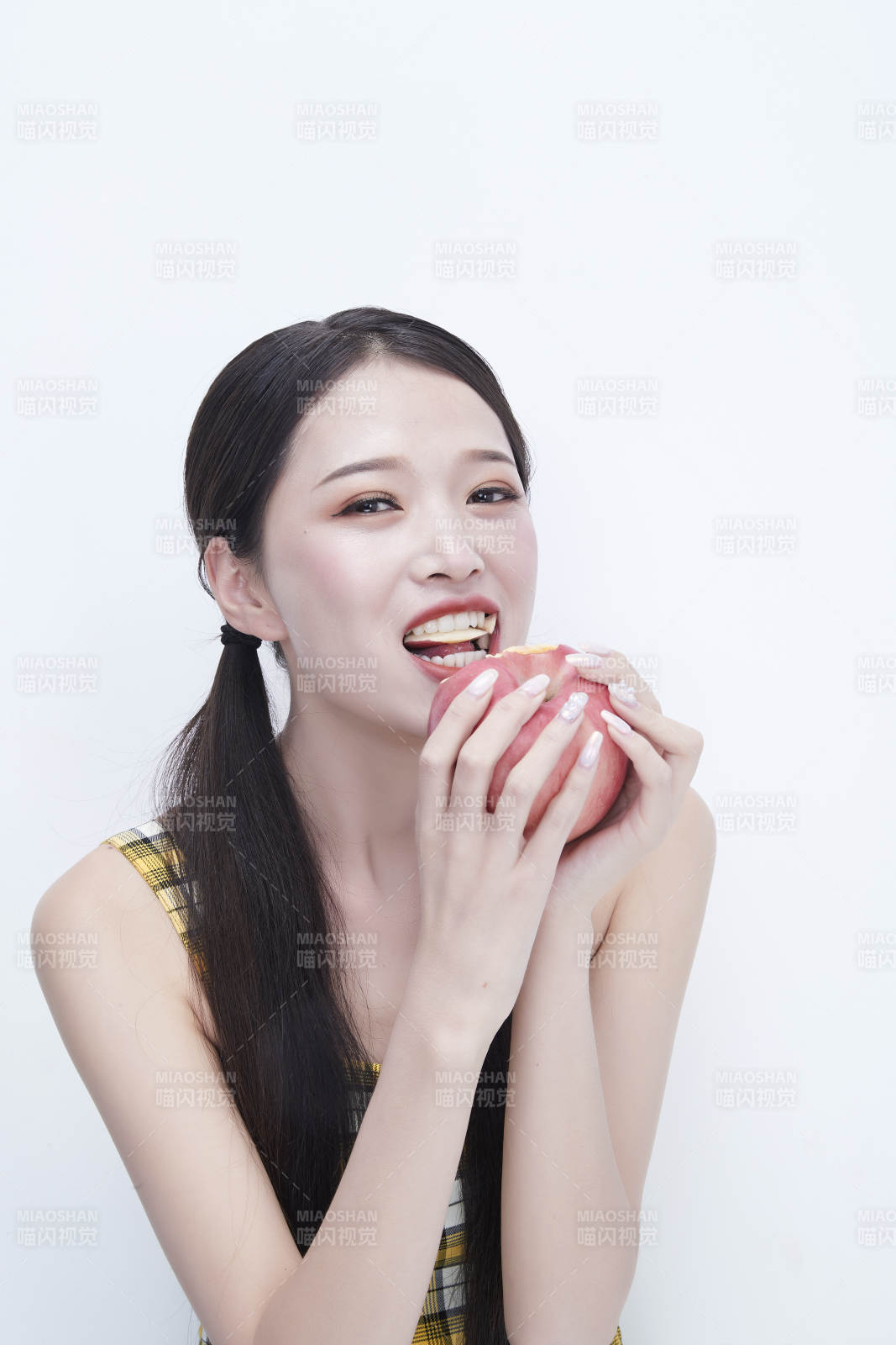 手拿苹果身穿格子吊带裙的亚洲可爱少女人像图片