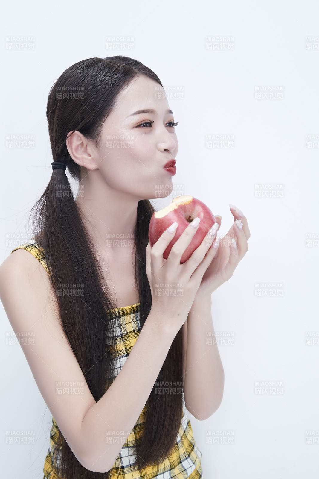 手拿苹果身穿格子吊带裙的亚洲可爱少女人像图片