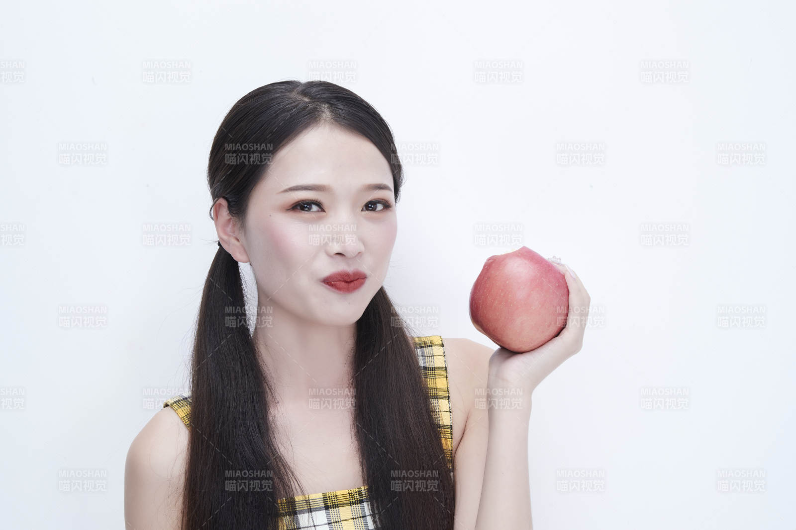 手拿苹果身穿格子吊带裙的亚洲可爱少女人像图片