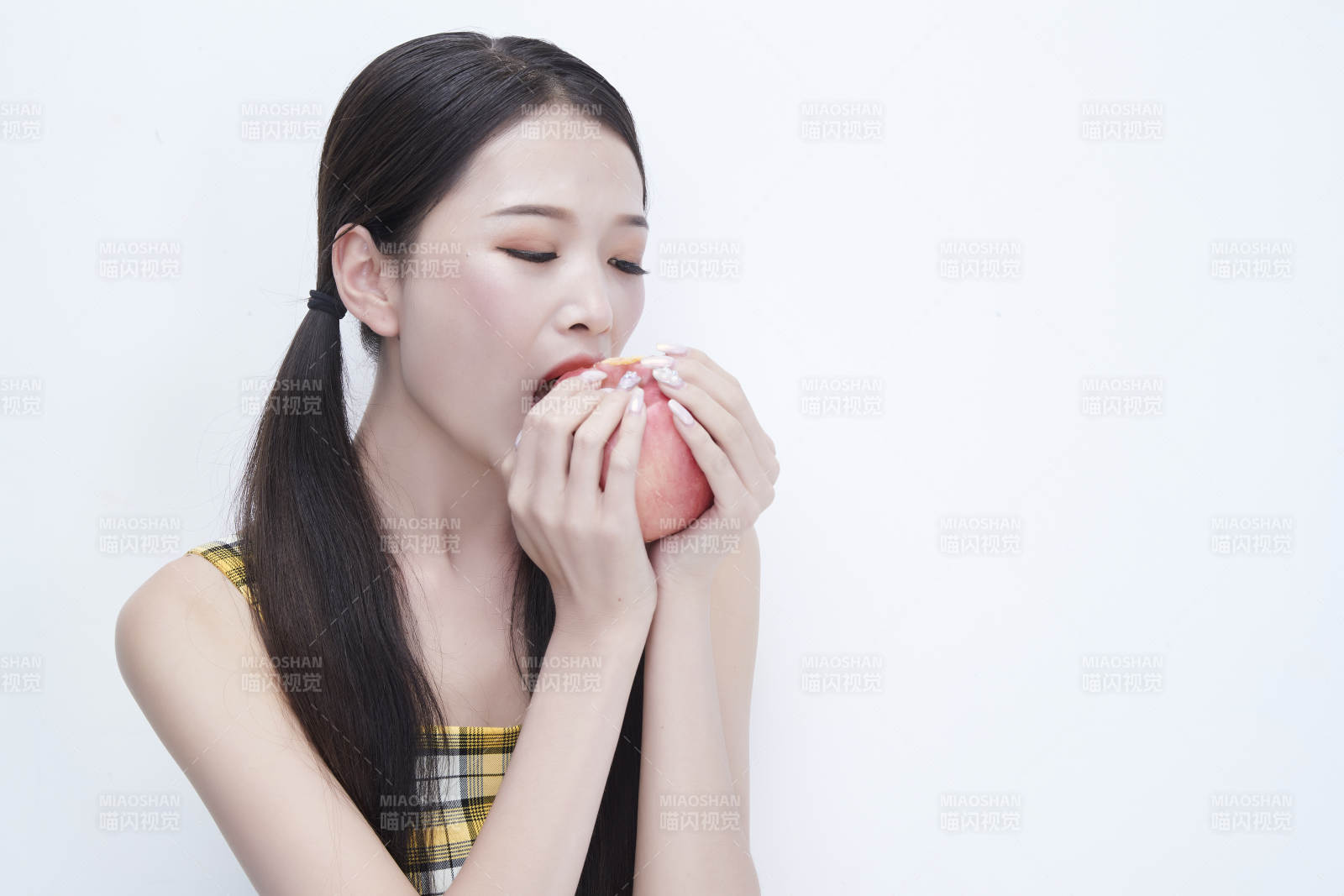 手拿苹果身穿格子吊带裙的亚洲可爱少女人像图片
