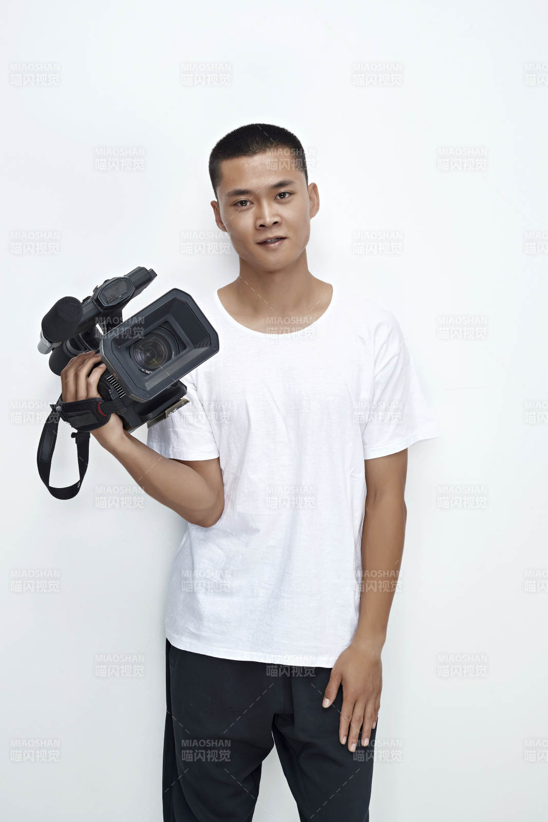 白色背景下手持摄像机进行录制拍摄的摄像师图片