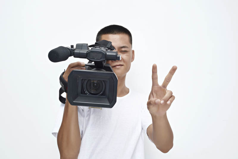 白色背景下手持摄像机进行录制拍摄的摄像师图片