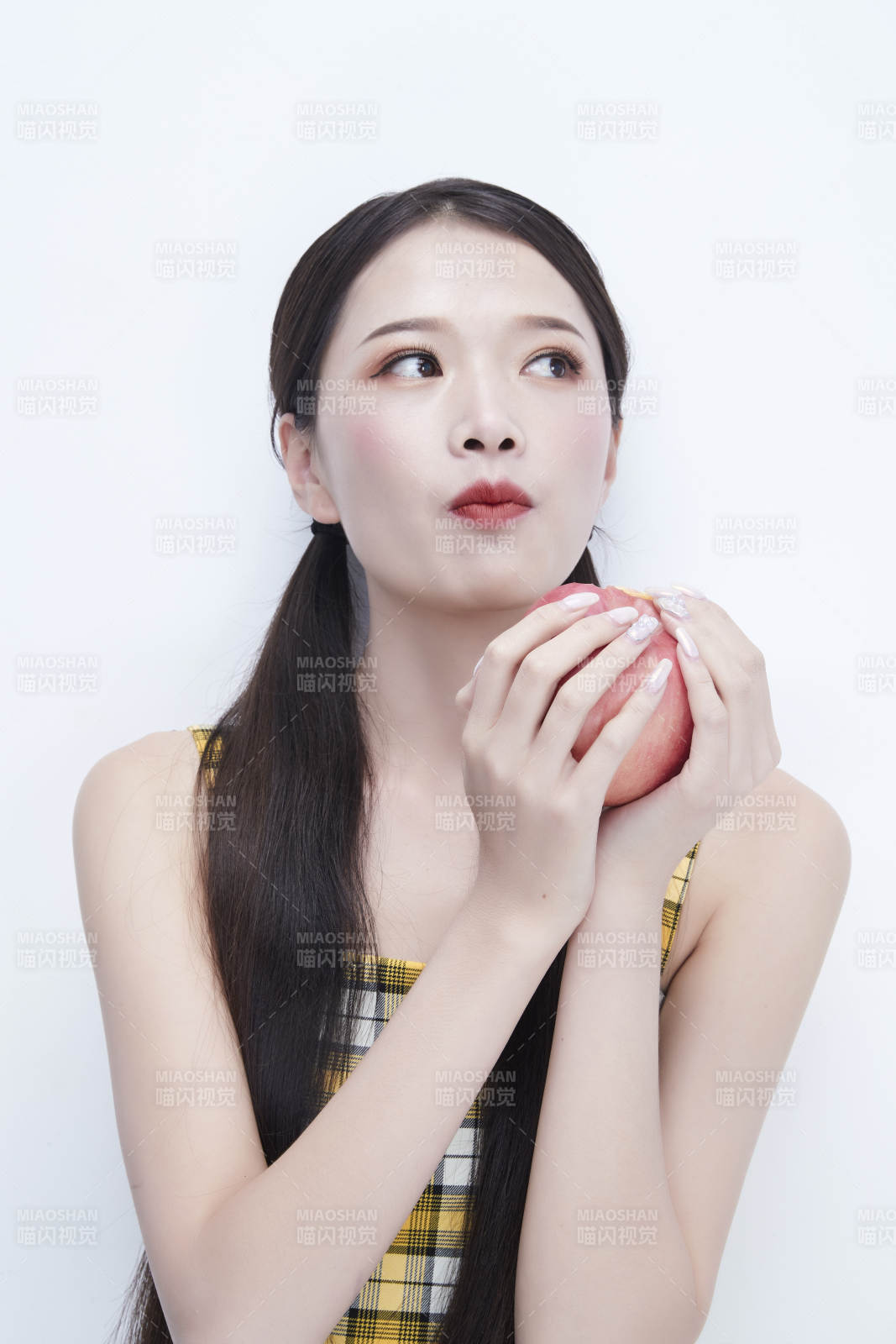 手拿苹果身穿格子吊带裙的亚洲可爱少女人像图片