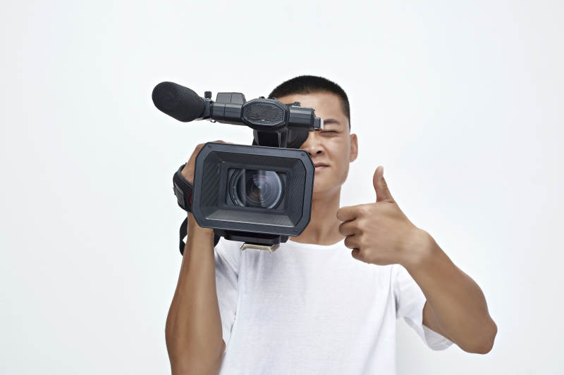 白色背景下手持摄像机进行录制拍摄的摄像师图片