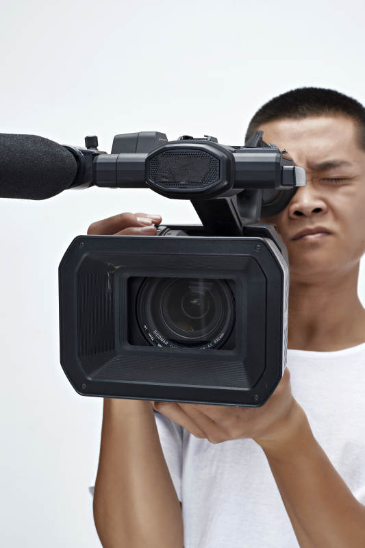 白色背景下手持摄像机进行录制拍摄的摄像师图片