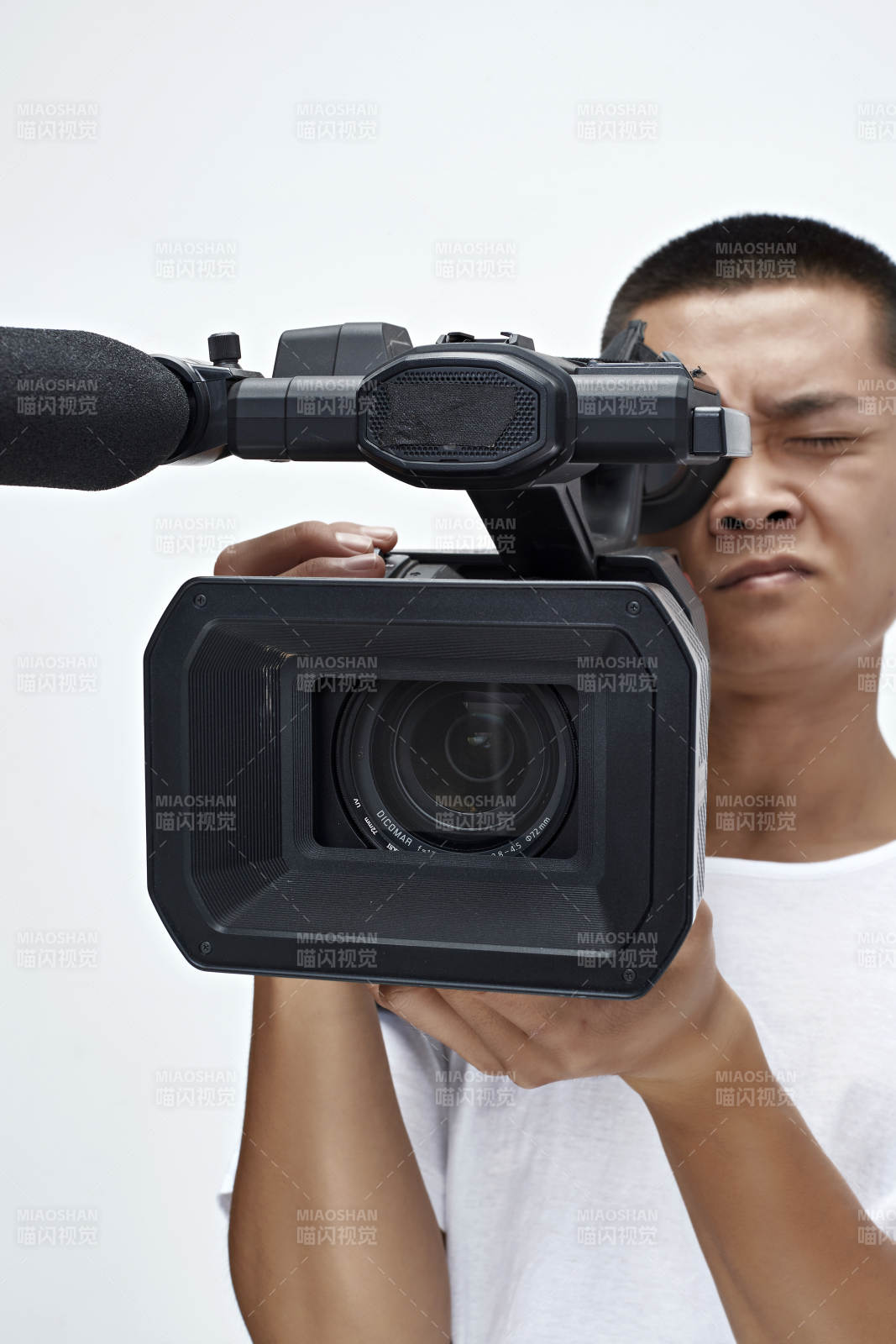 白色背景下手持摄像机进行录制拍摄的摄像师图片