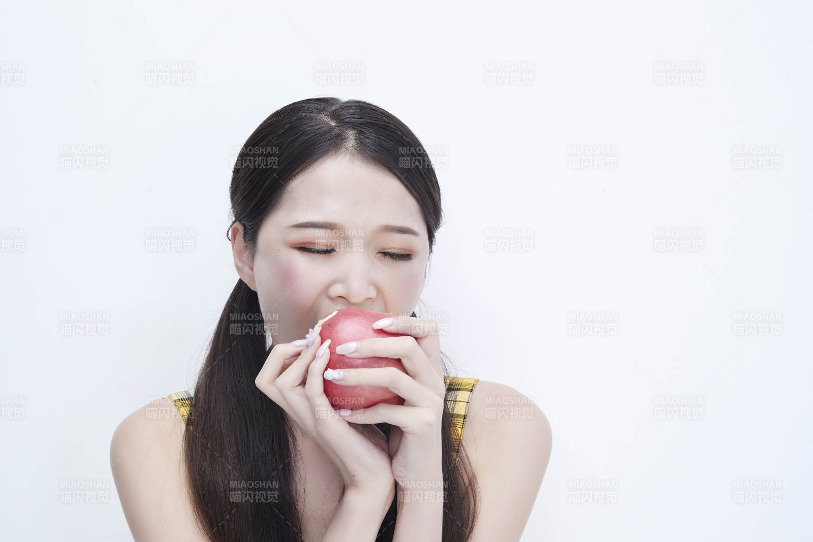 手拿苹果身穿格子吊带裙的亚洲可爱少女人像图片