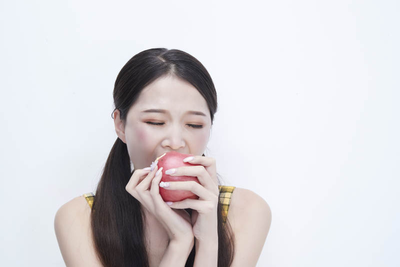 手拿苹果身穿格子吊带裙的亚洲可爱少女人像图片