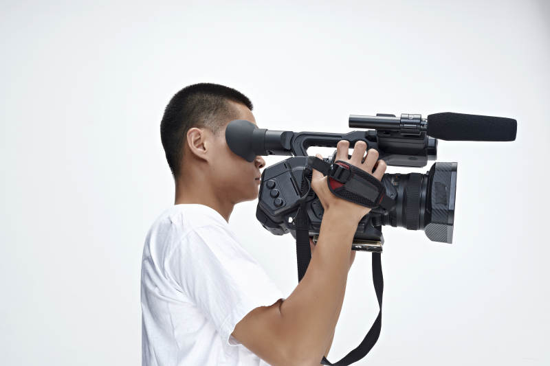 白色背景下手持摄像机进行录制拍摄的摄像师图片