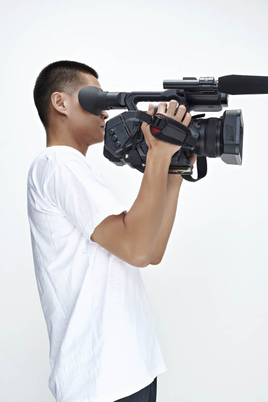 白色背景下手持摄像机进行录制拍摄的摄像师图片