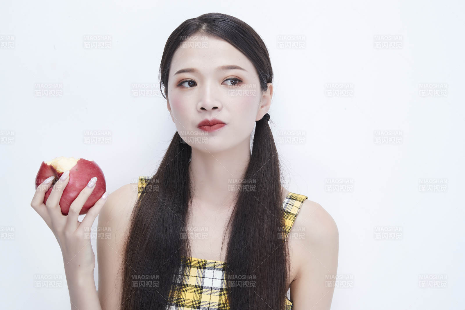 手拿苹果身穿格子吊带裙的亚洲可爱少女人像图片