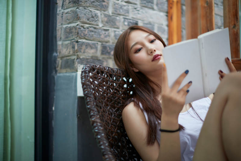 院子里坐在长椅上阅读书籍的亚洲长发少女图片