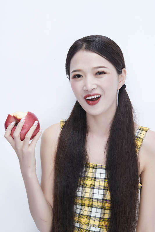 手拿苹果身穿格子吊带裙的亚洲可爱少女人像图片
