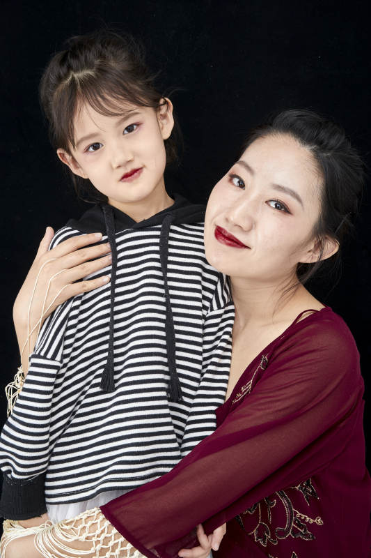 黑色背景的美丽妈妈与可爱女儿亲子人像图片