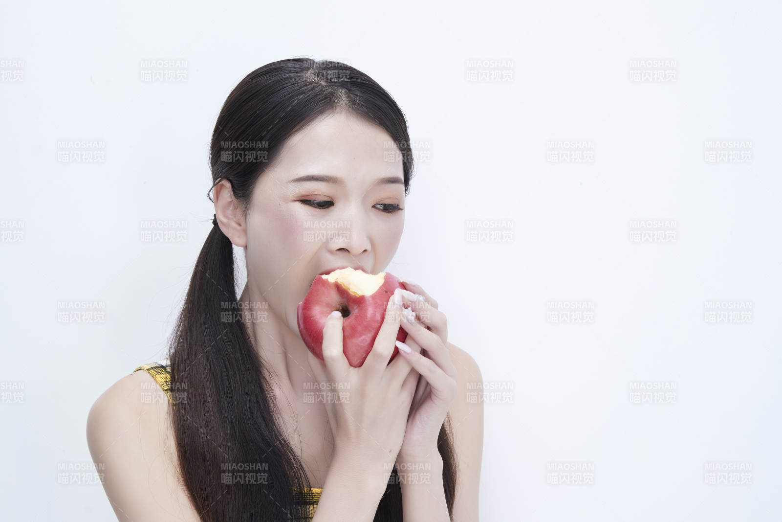 手拿苹果身穿格子吊带裙的亚洲可爱少女人像图片