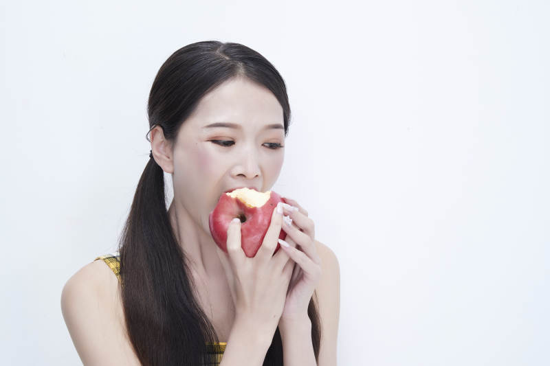 手拿苹果身穿格子吊带裙的亚洲可爱少女人像图片