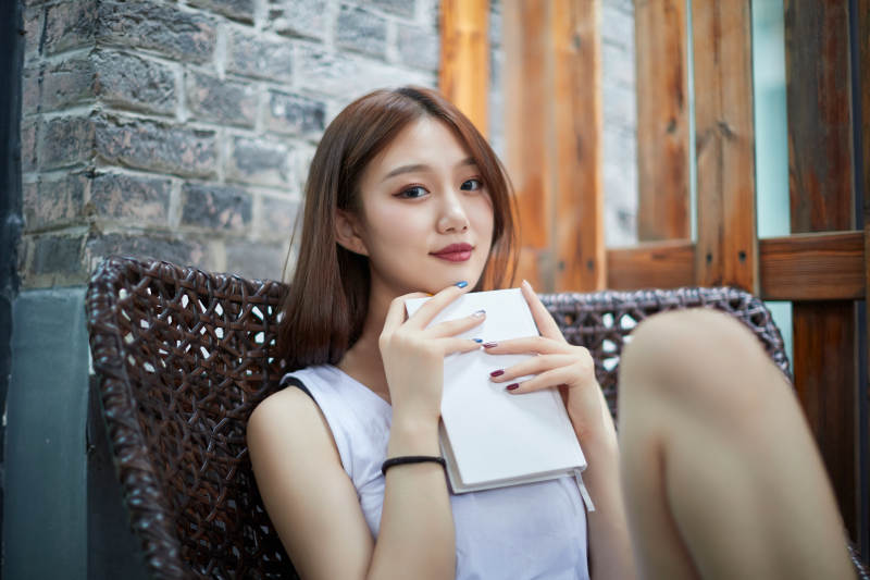 院子里坐在长椅上阅读书籍的亚洲长发少女图片