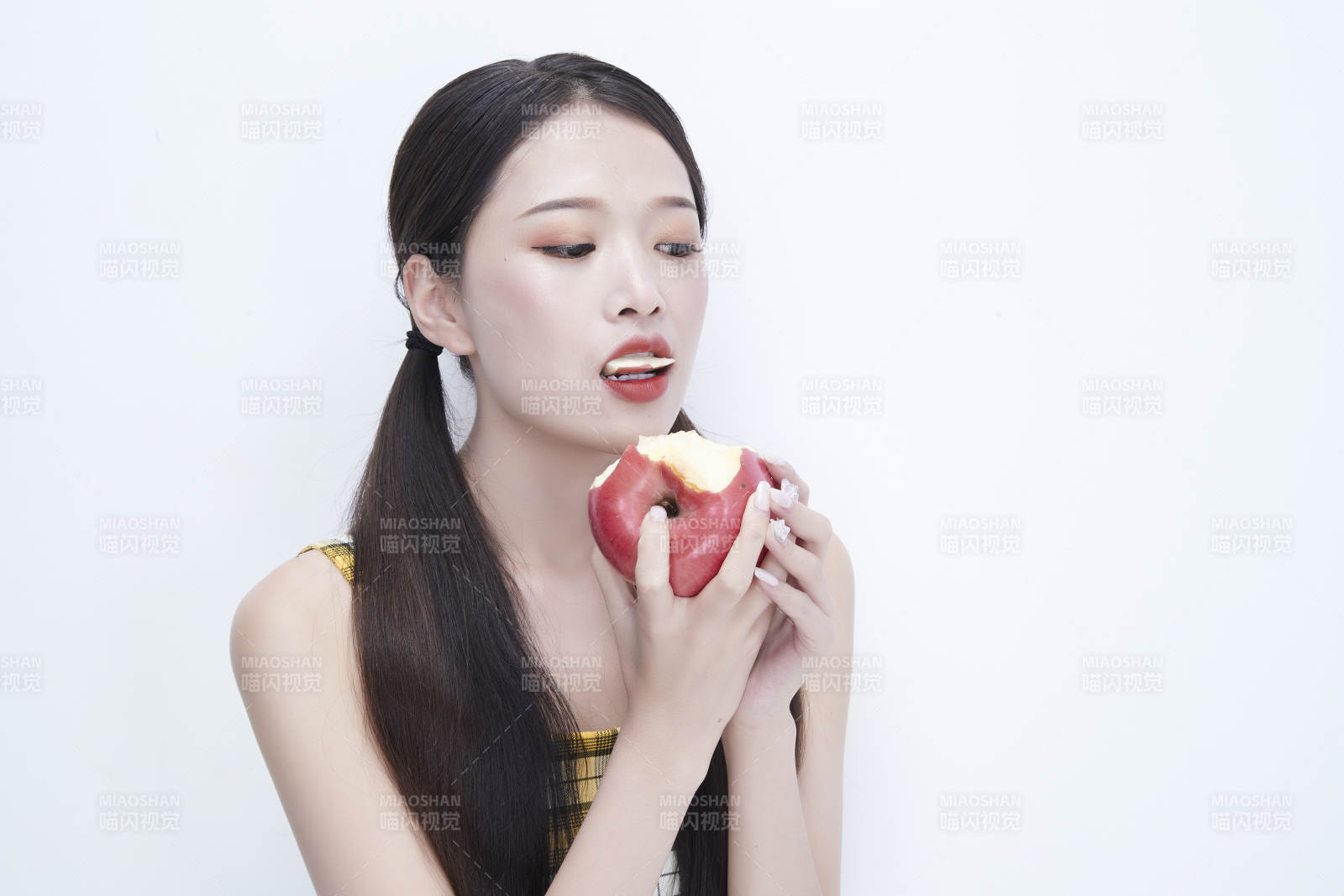 手拿苹果身穿格子吊带裙的亚洲可爱少女人像图片