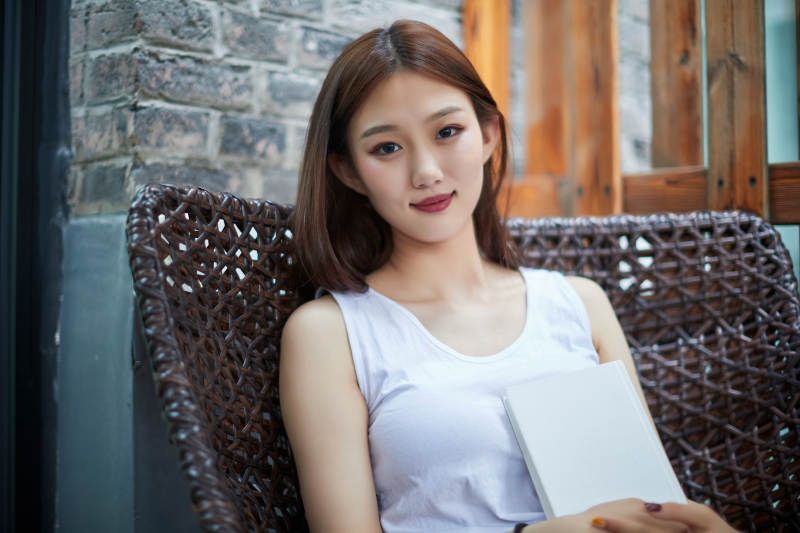 院子里坐在长椅上阅读书籍的亚洲长发少女图片