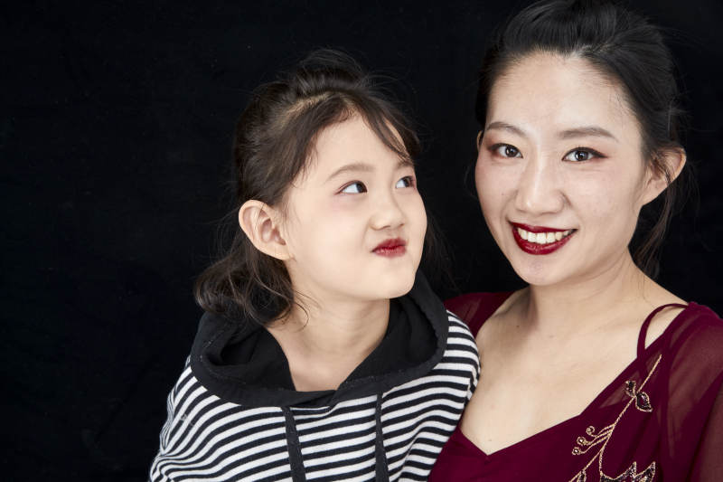 黑色背景的美丽妈妈与可爱女儿亲子人像图片