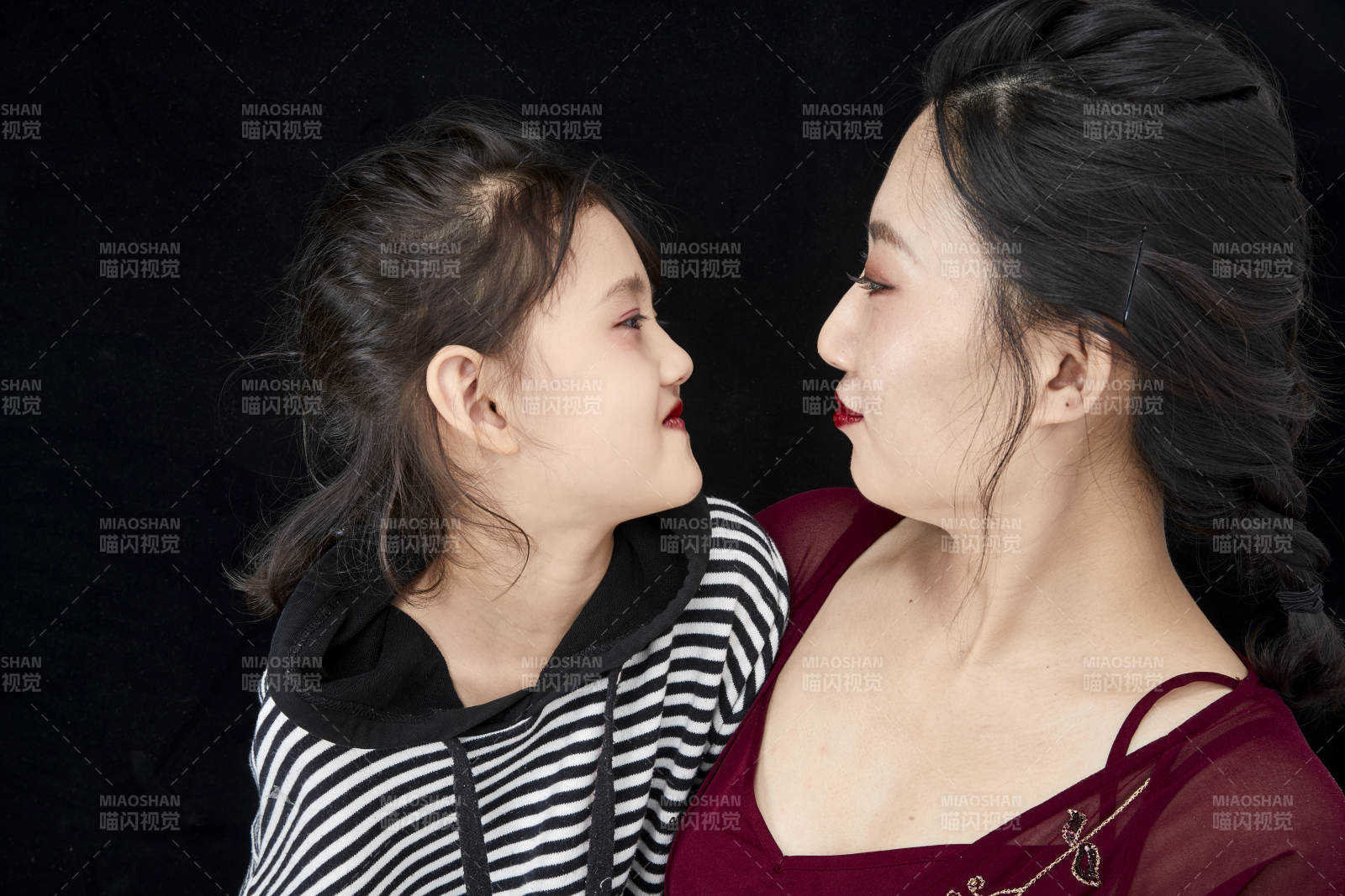 黑色背景的美丽妈妈与可爱女儿亲子人像图片