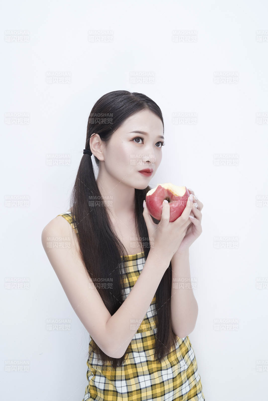 手拿苹果身穿格子吊带裙的亚洲可爱少女人像图片