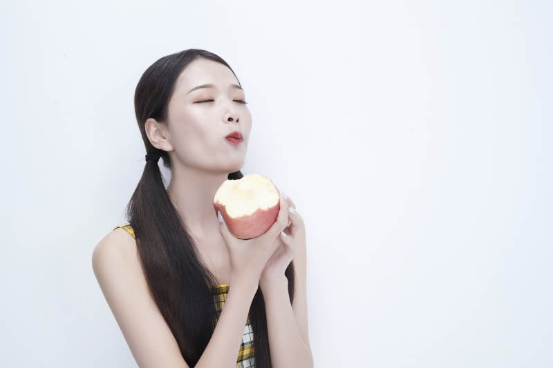 手拿苹果身穿格子吊带裙的亚洲可爱少女人像图片