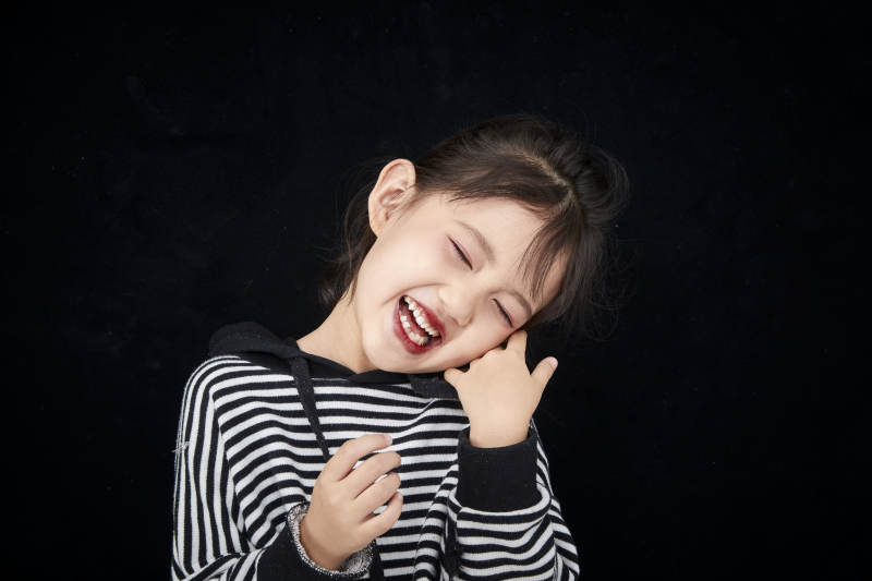 黑色背景的调皮可爱的亚洲小女孩儿童图片