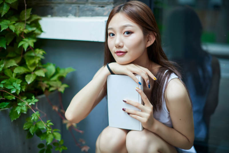 院子里坐在长椅上阅读书籍的亚洲长发少女图片