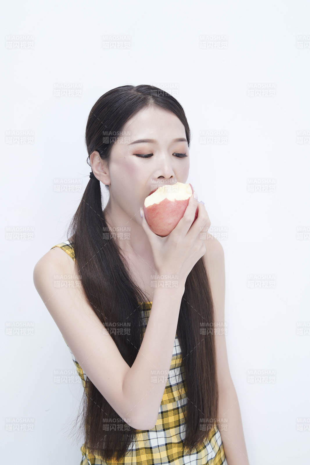 手拿苹果身穿格子吊带裙的亚洲可爱少女人像图片