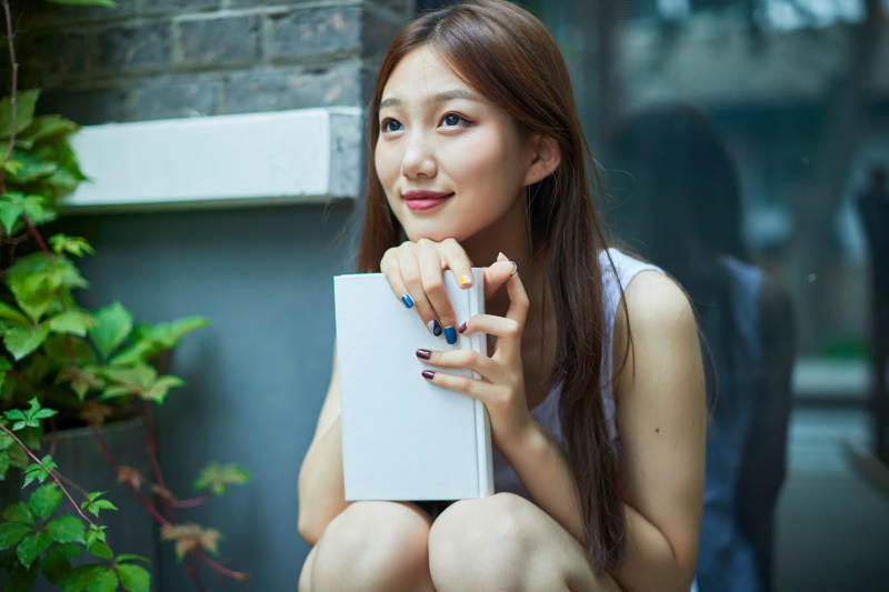 院子里坐在长椅上阅读书籍的亚洲长发少女图片