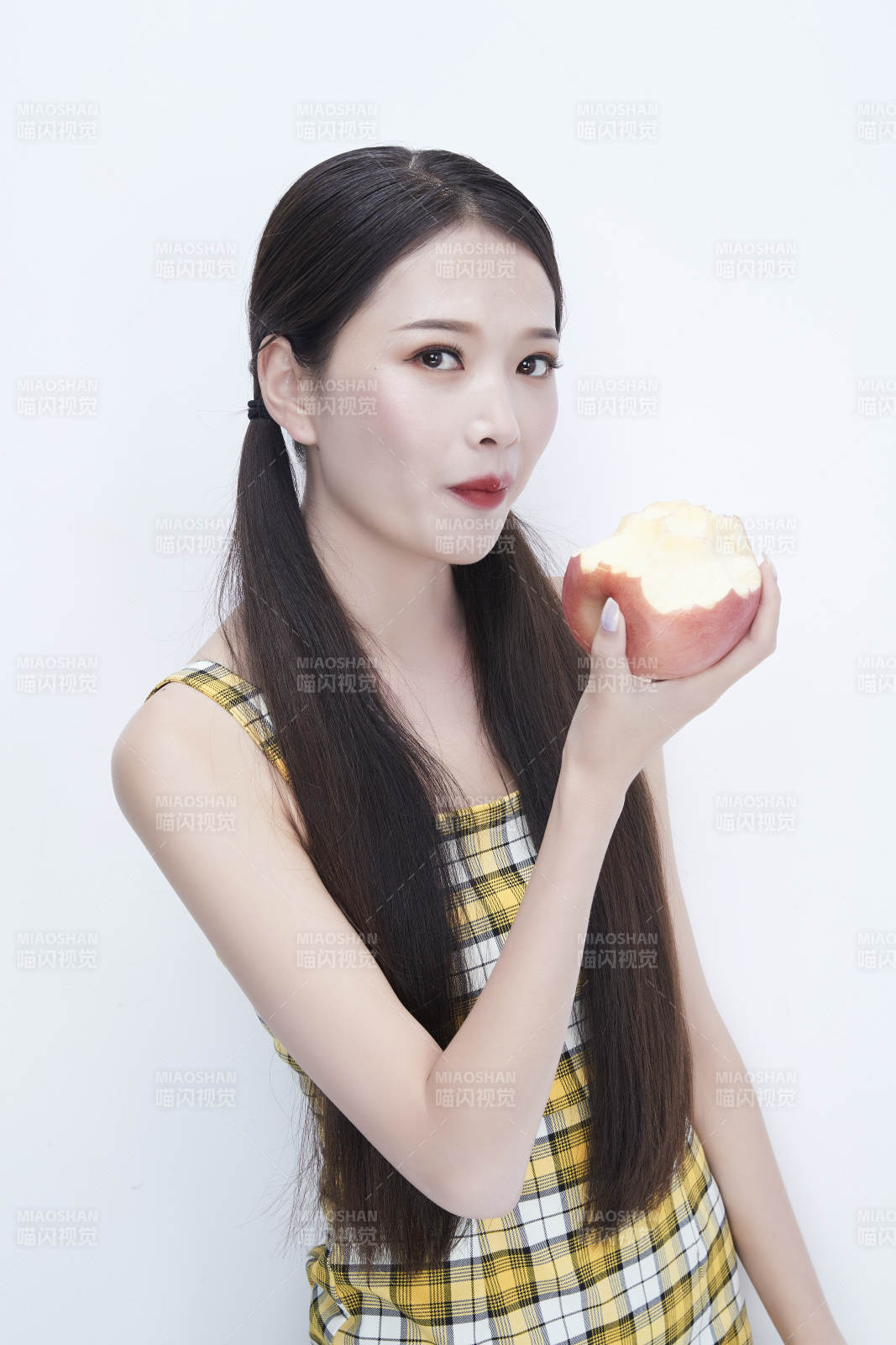 手拿苹果身穿格子吊带裙的亚洲可爱少女人像图片
