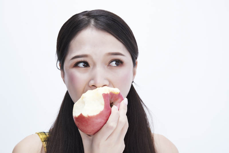 手拿苹果身穿格子吊带裙的亚洲可爱少女人像图片