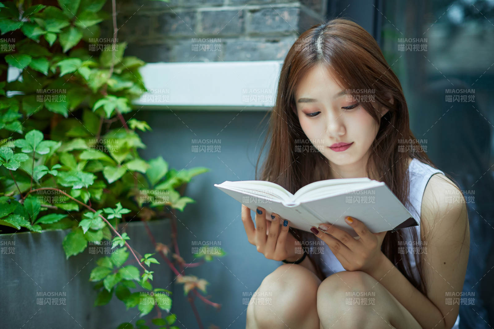 院子里坐在长椅上阅读书籍的亚洲长发少女图片