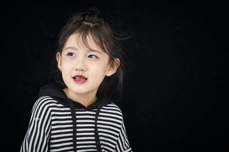 黑色背景的调皮可爱的亚洲小女孩儿童图片