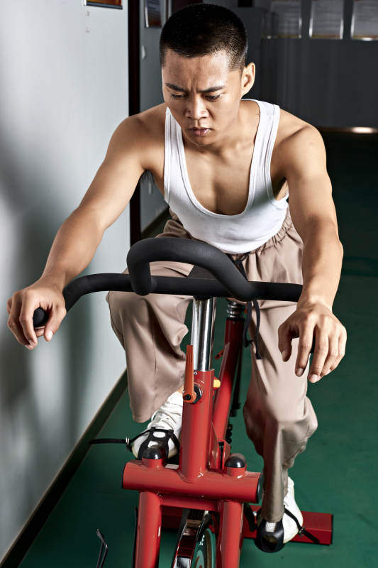 在室内进行动感单车锻炼的亚洲健身男士形象图片