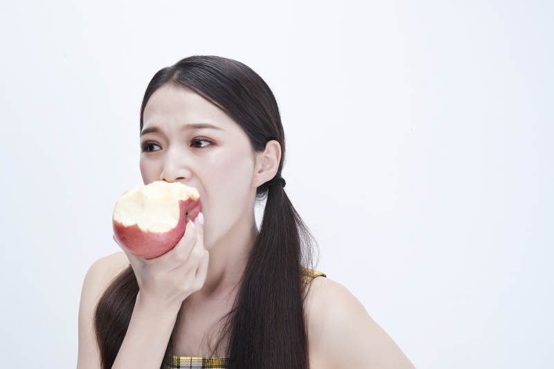 手拿苹果身穿格子吊带裙的亚洲可爱少女人像图片