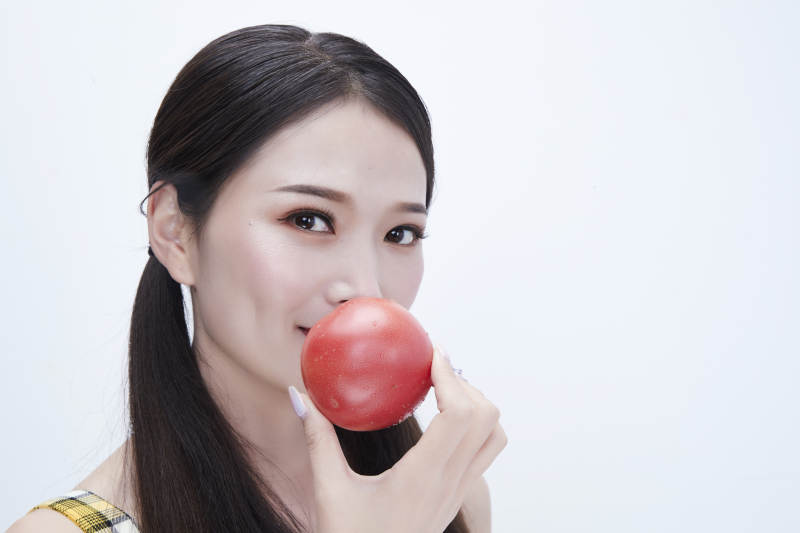 啃咬番茄身穿格子吊带裙的亚洲可爱少女人像图片