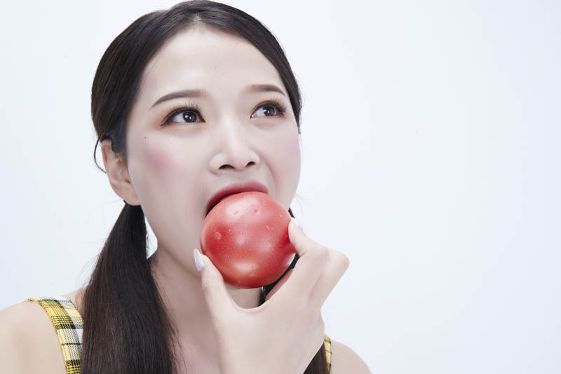 啃咬番茄身穿格子吊带裙的亚洲可爱少女人像图片