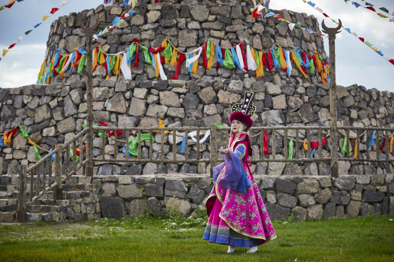 草原上敖包前身穿豪华蒙古族服饰的蒙族少女图片