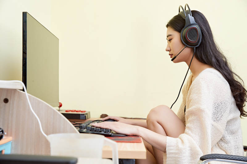 在家里坐在椅子上打游戏的美丽女孩图片