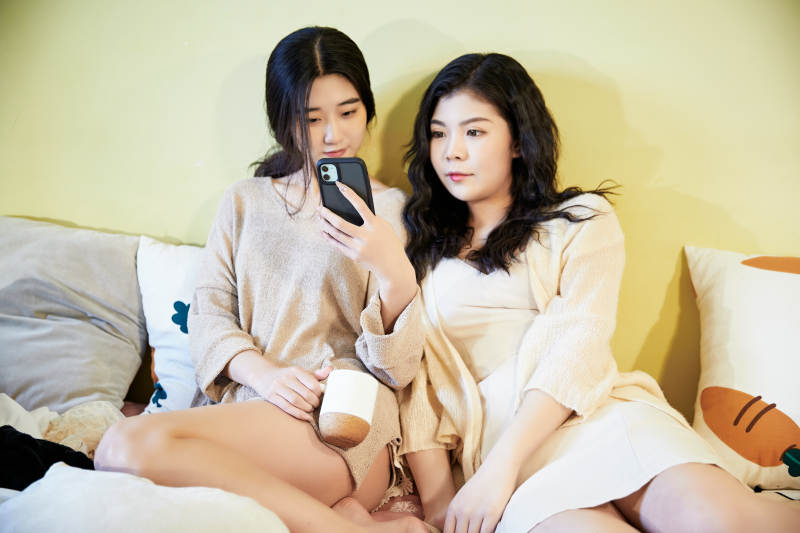 坐在床上玩手机的俩位美女图片