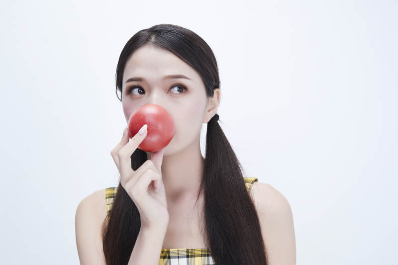 啃咬番茄身穿格子吊带裙的亚洲可爱少女人像图片