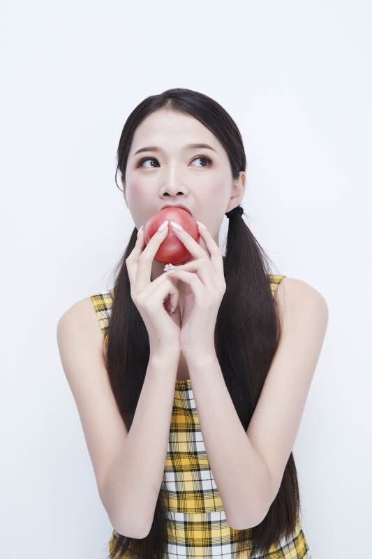 啃咬番茄身穿格子吊带裙的亚洲可爱少女人像图片