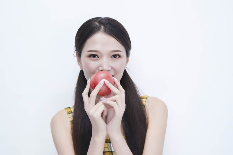 啃咬番茄身穿格子吊带裙的亚洲可爱少女人像图片